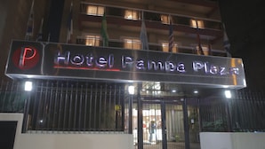 Hotel Pampa Plaza with a prominent illuminated sign, a gated entrance, and multiple flags.