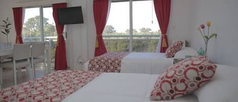 A hotel room with two beds, a desk, and a TV.