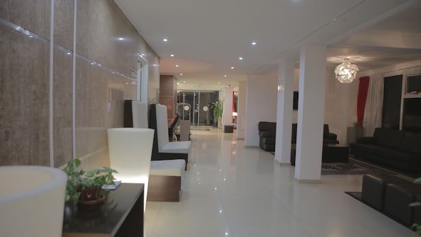 A modern hotel lobby with a clean, polished floor, a reception desk, and a seating area with sofas and a coffee table.