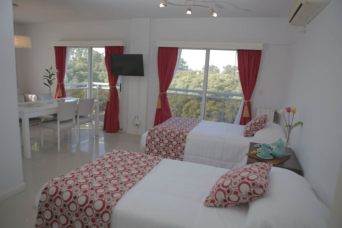 A hotel room with two beds, a desk, and a TV.