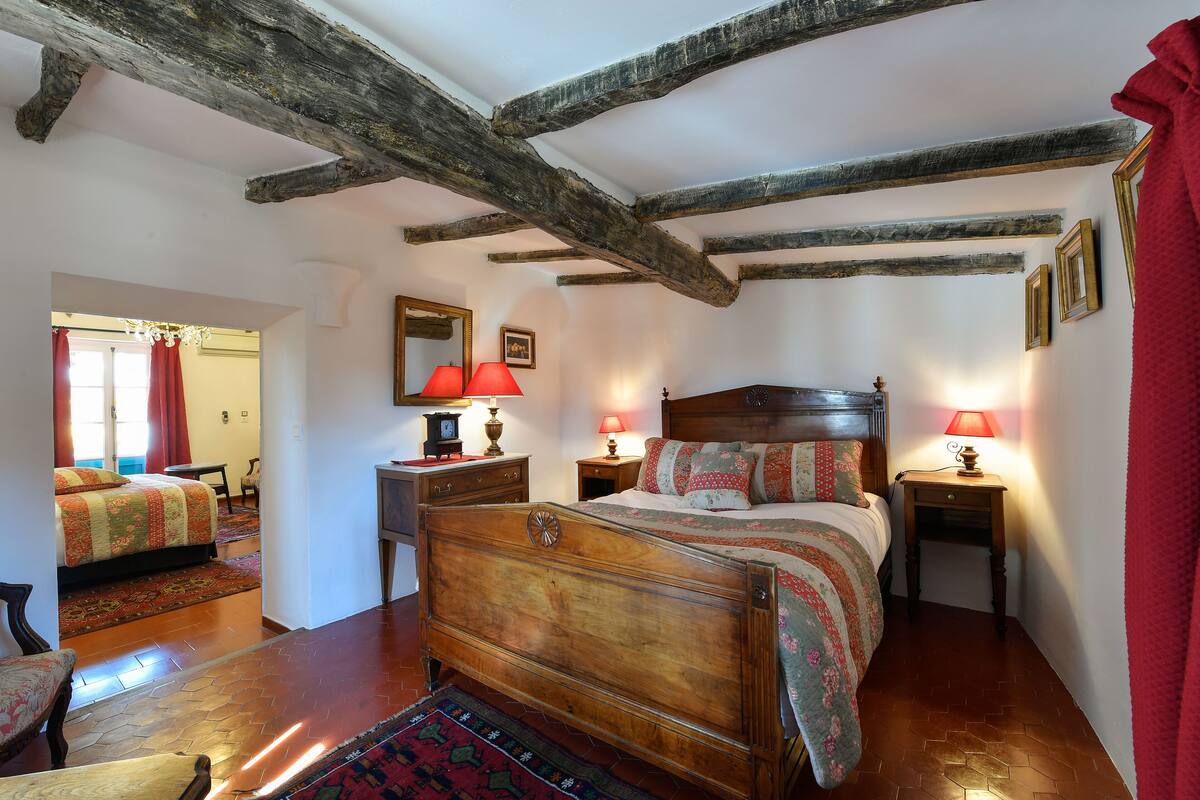 A bedroom with a wooden bed, two bedside tables with lamps, a mirror, and a red curtain.