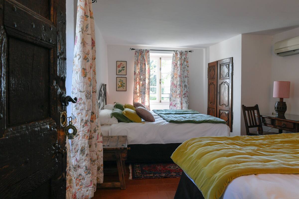 A bedroom with a bed, a wooden door, a desk, and a chair.