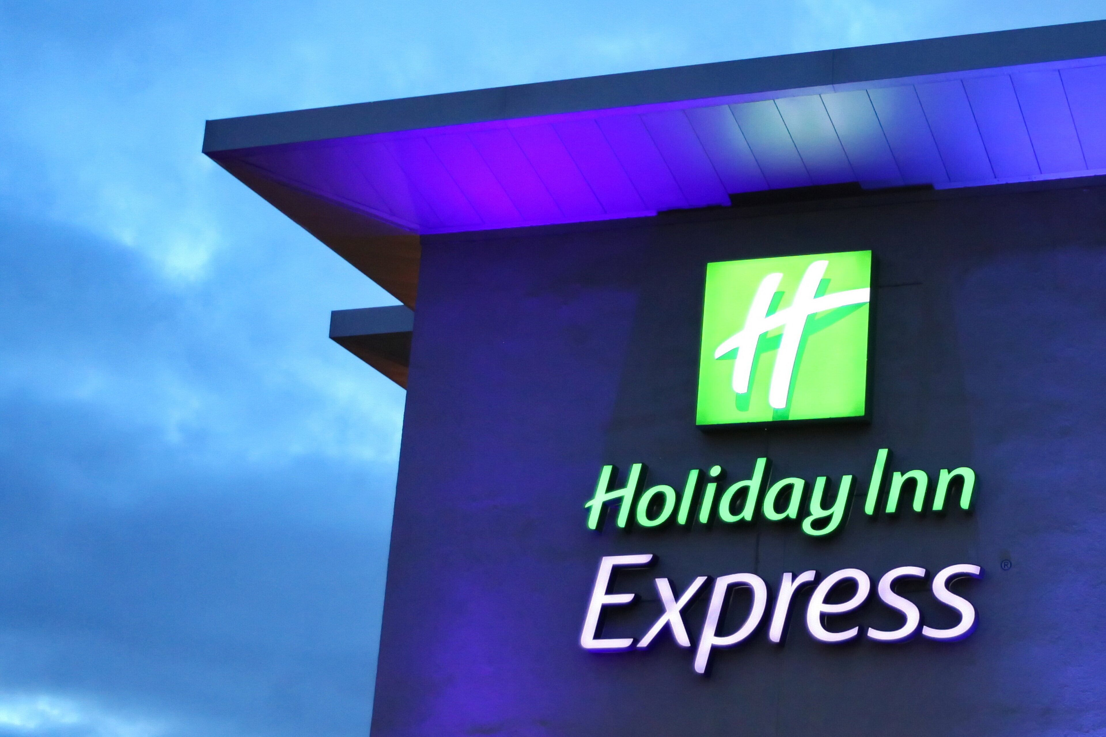 Une enseigne Holiday Inn Express avec un logo vert et un éclairage néon.