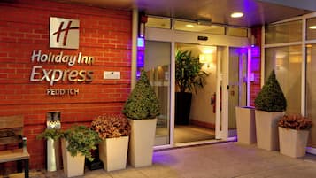 Exterior de un edificio Holiday Inn Express con fachada de ladrillo, entrada de vidrio y plantas en macetas.