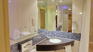 Une salle de bain moderne avec une étagère en verre, un lavabo et un miroir.