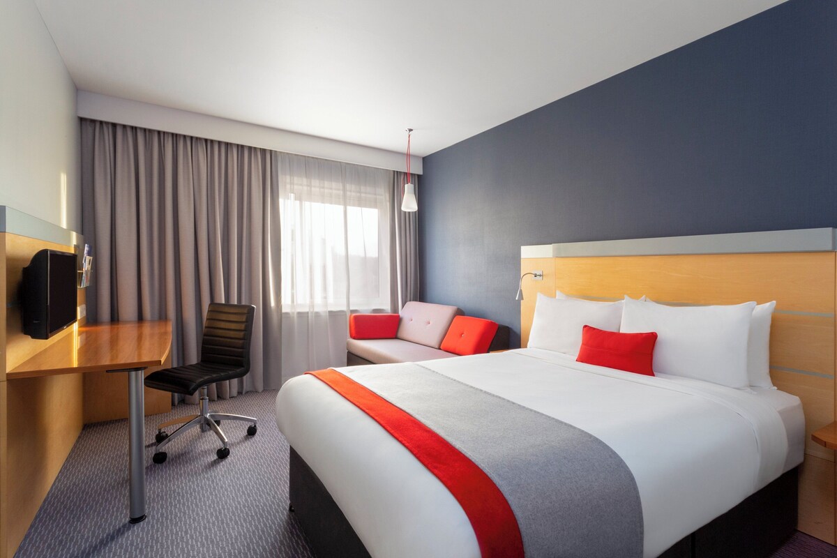 Une chambre d’hôtel avec un grand lit, un bureau, une chaise et un téléviseur.