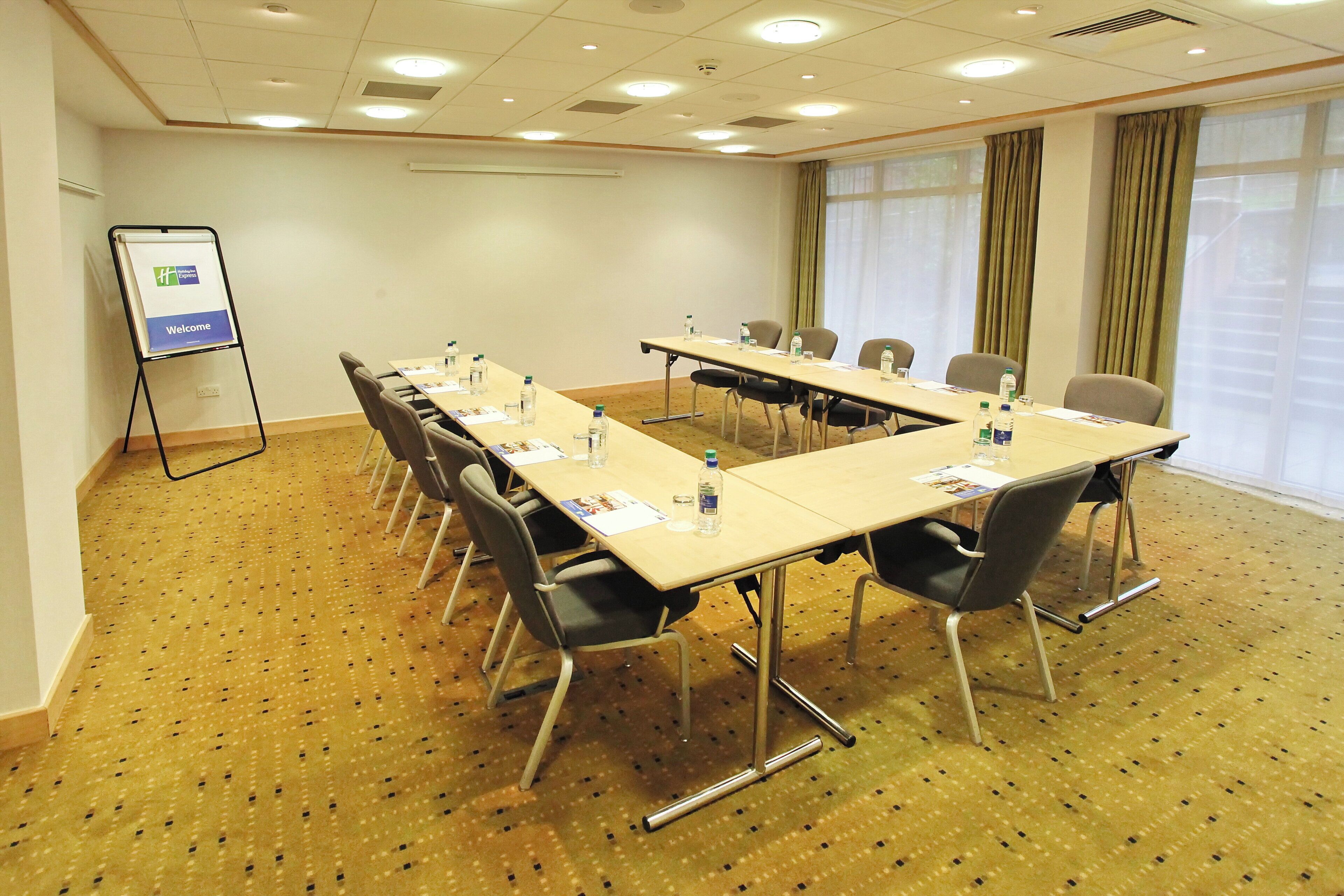 A conference room with a long table, chairs, water bottles, and a flip chart.