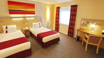A hotel room with two beds, a desk, and a chair.
