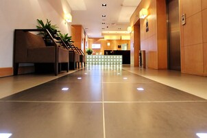 A hotel lobby with a reception desk, seating area, and a staircase.