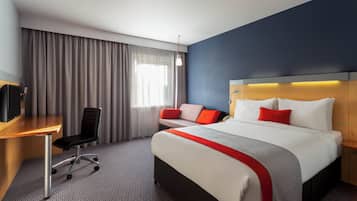 Een hotelkamer met een bed, een bureau, een stoel en een televisie.