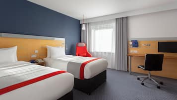 A hotel room with two beds, a desk, a chair, and a television.
