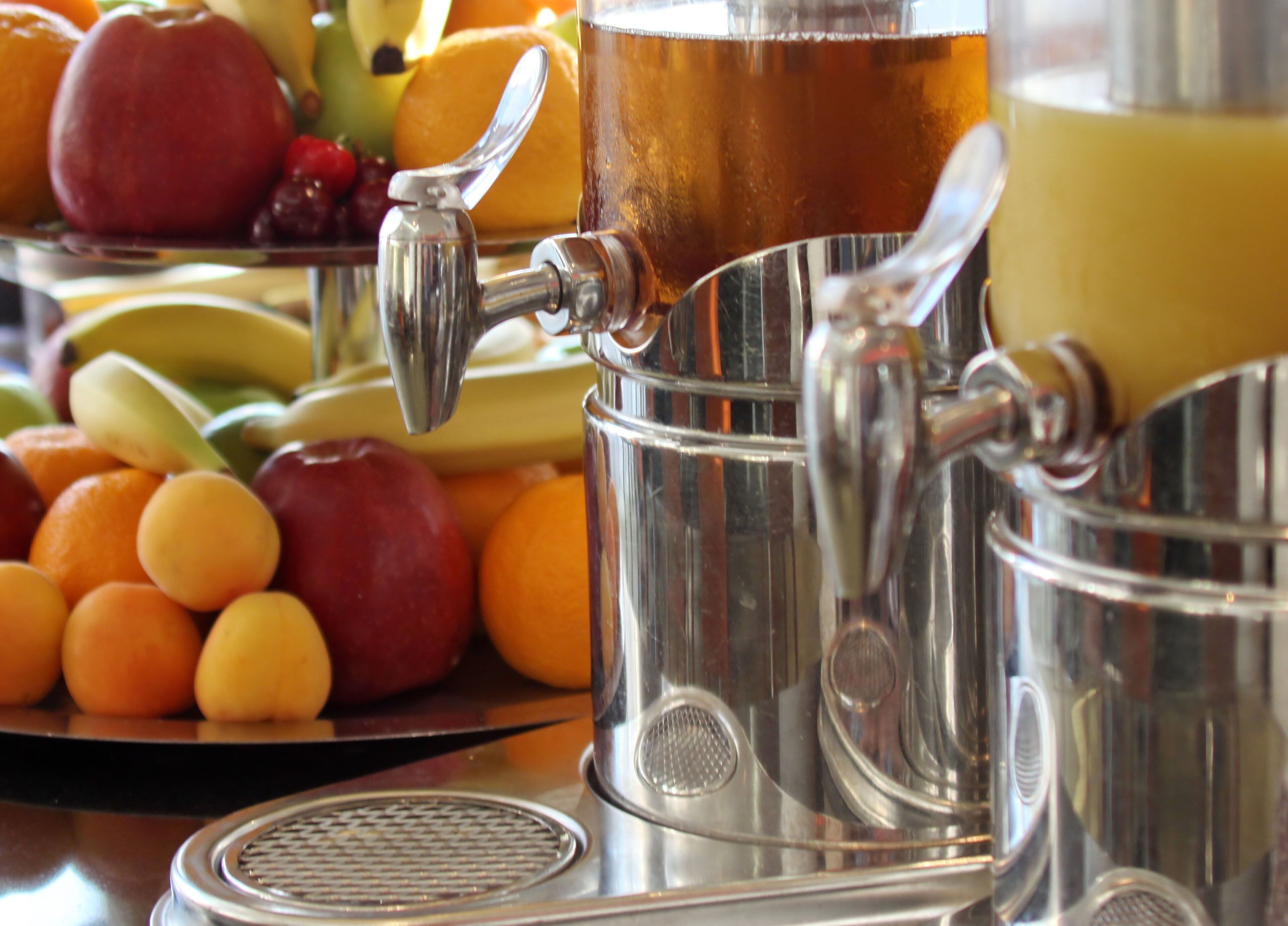 A juicer with fruits and a glass of juice.