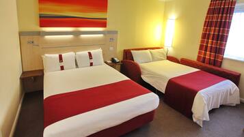 A hotel room with two beds, a nightstand, a lamp, and a painting on the wall.