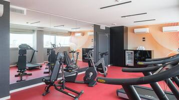 A gym with exercise equipment, a treadmill, and a mirrored wall.