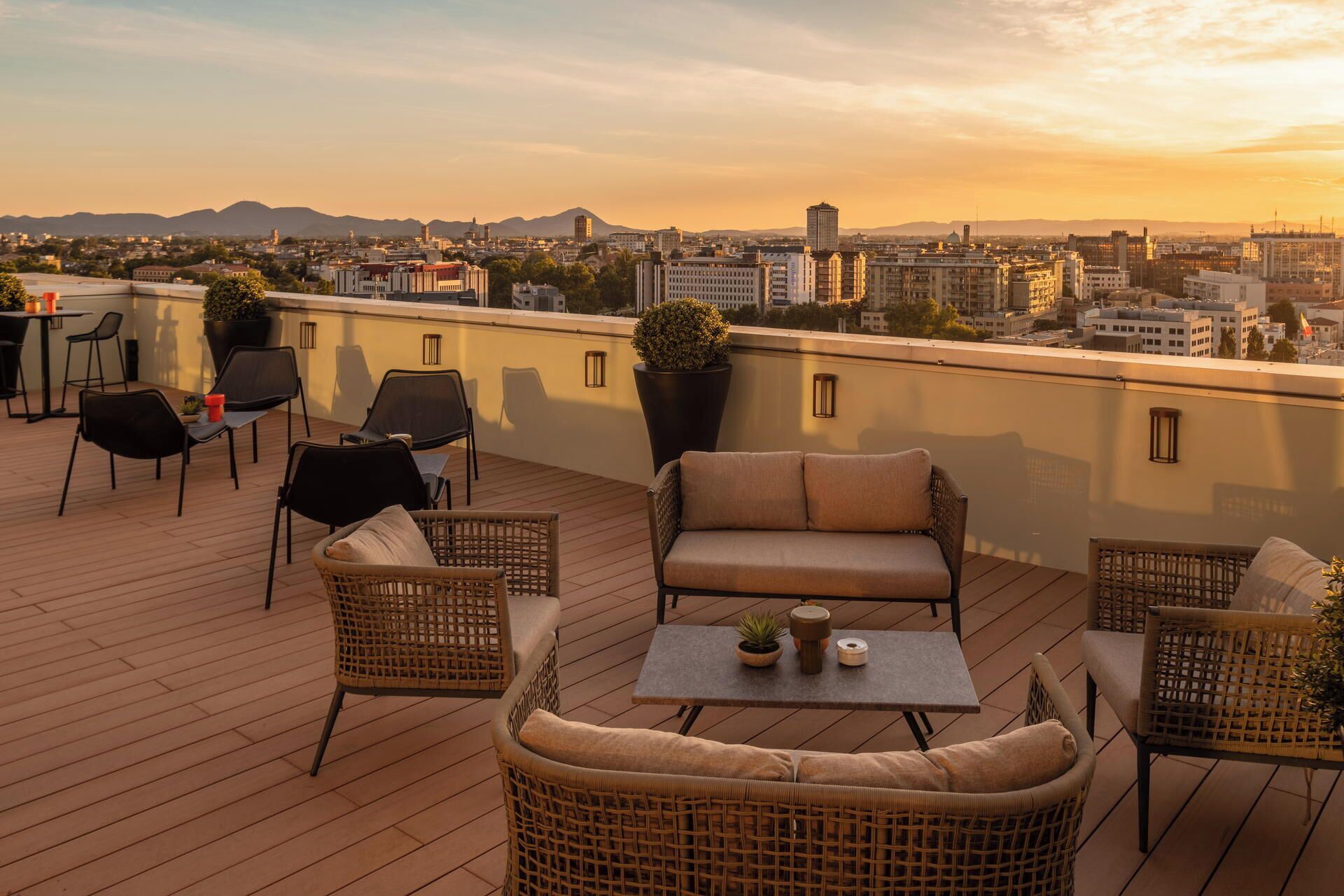 Eine Dachterrasse mit Korbmöbeln, einem Tisch und Topfpflanzen.