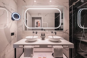 Un baño moderno con dos lavamanos, un espejo grande con iluminación integrada y zona de ducha.