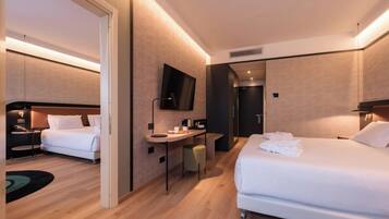 Habitación de hotel con dos camas, un escritorio, un televisor y la puerta del baño.