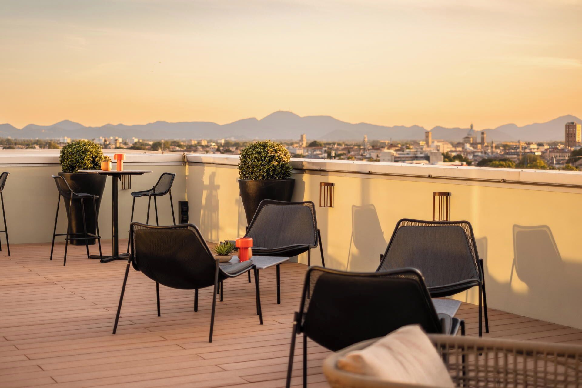 Terraço no telhado com área de estar ao ar livre, plantas em vasos e vista para a cidade.