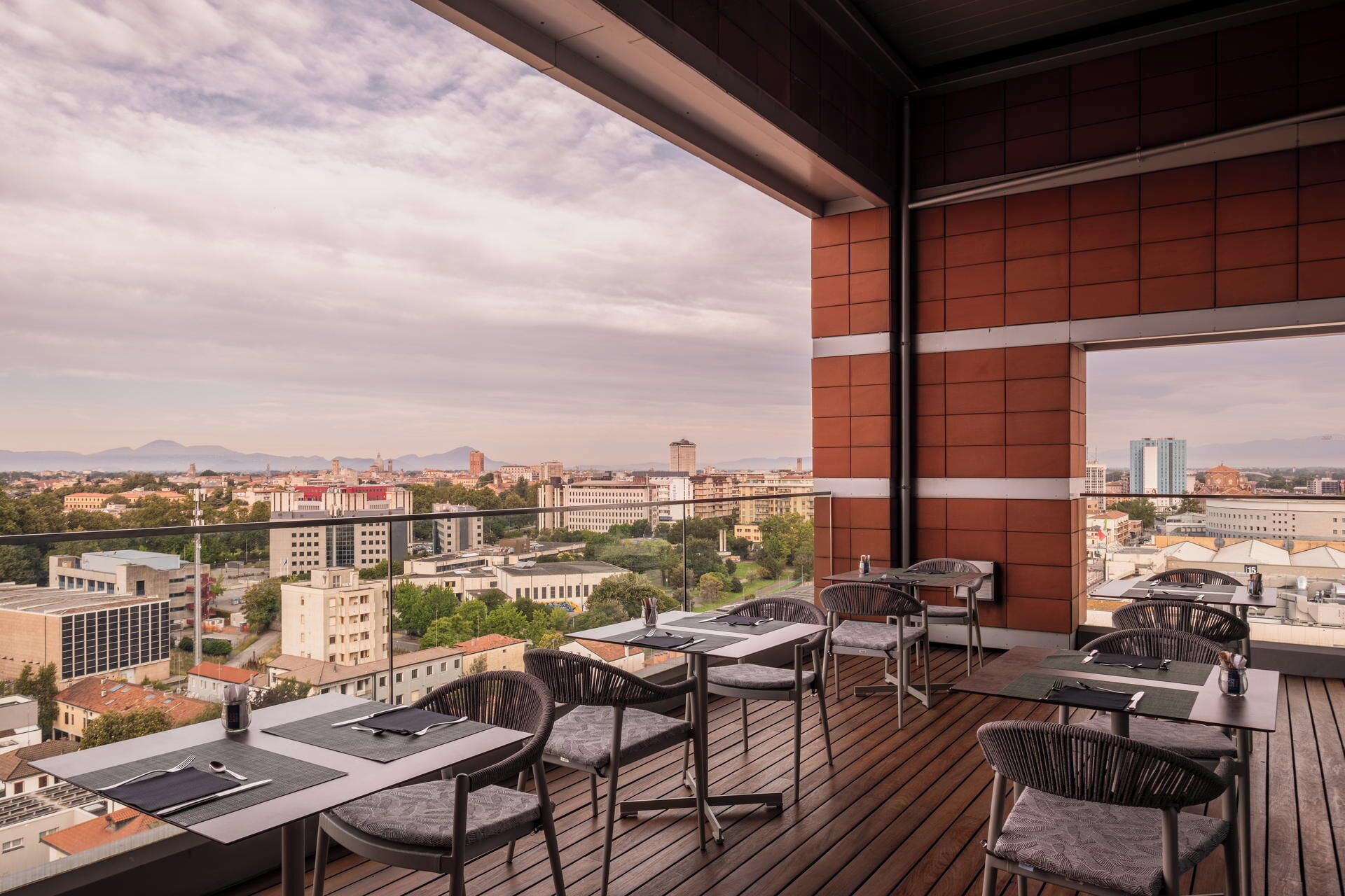 A balcony with outdoor seating, a city view, and a brick wall.