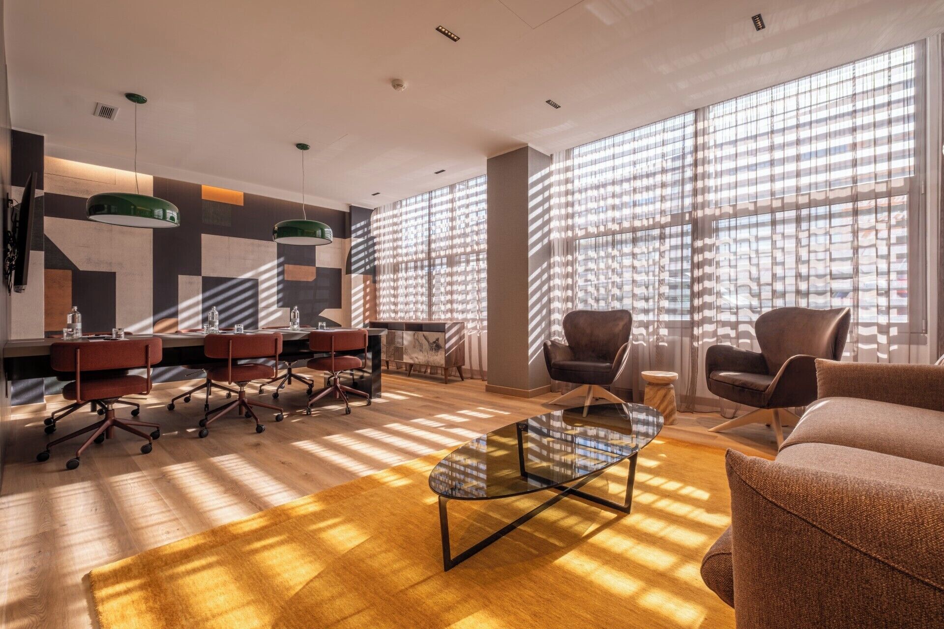 A modern meeting room with a glass table, leather chairs, and a sofa.