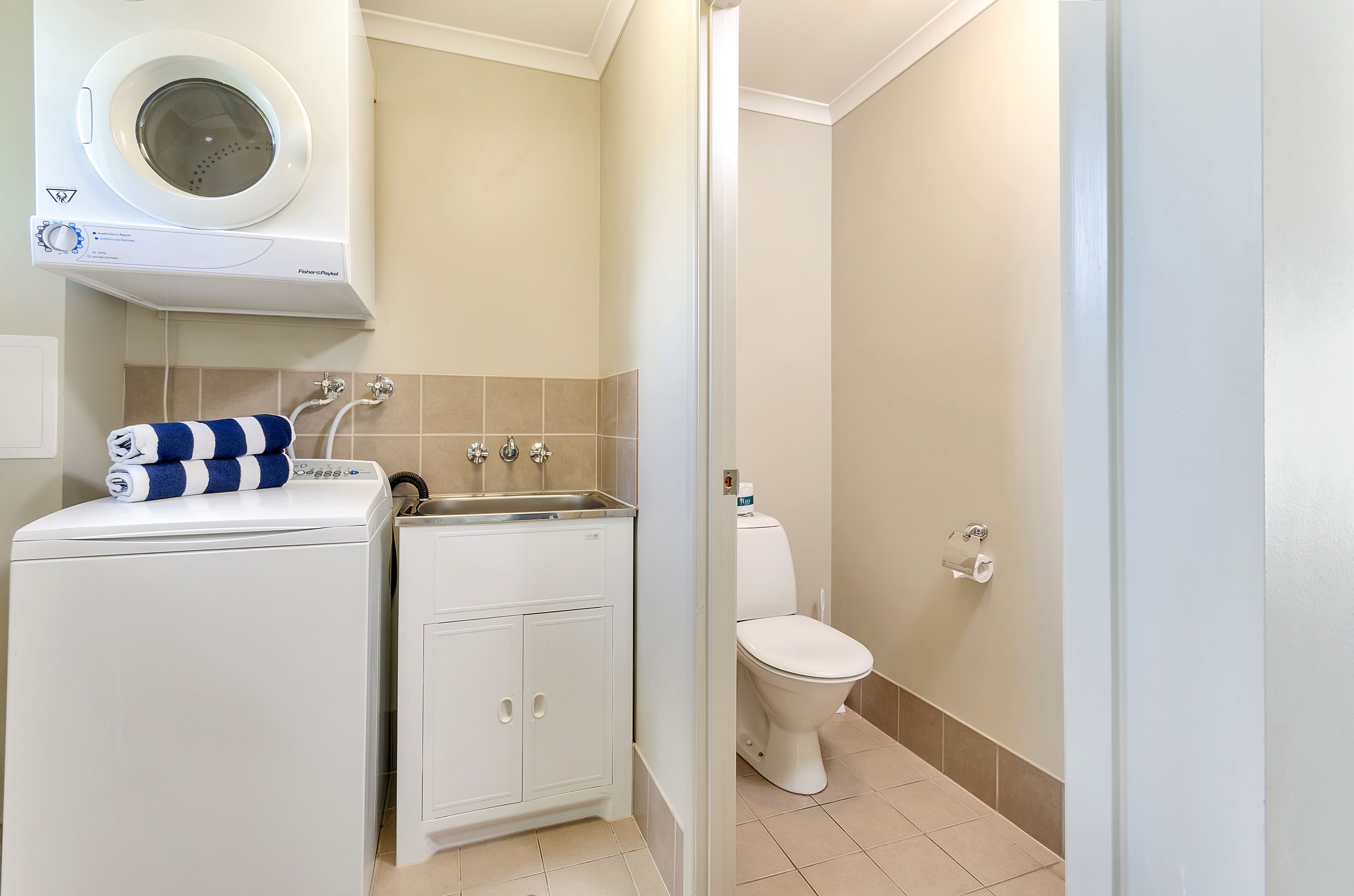 A compact bathroom with a washing machine, a sink, and a toilet.