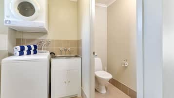 A compact bathroom with a washing machine, a sink, and a toilet.