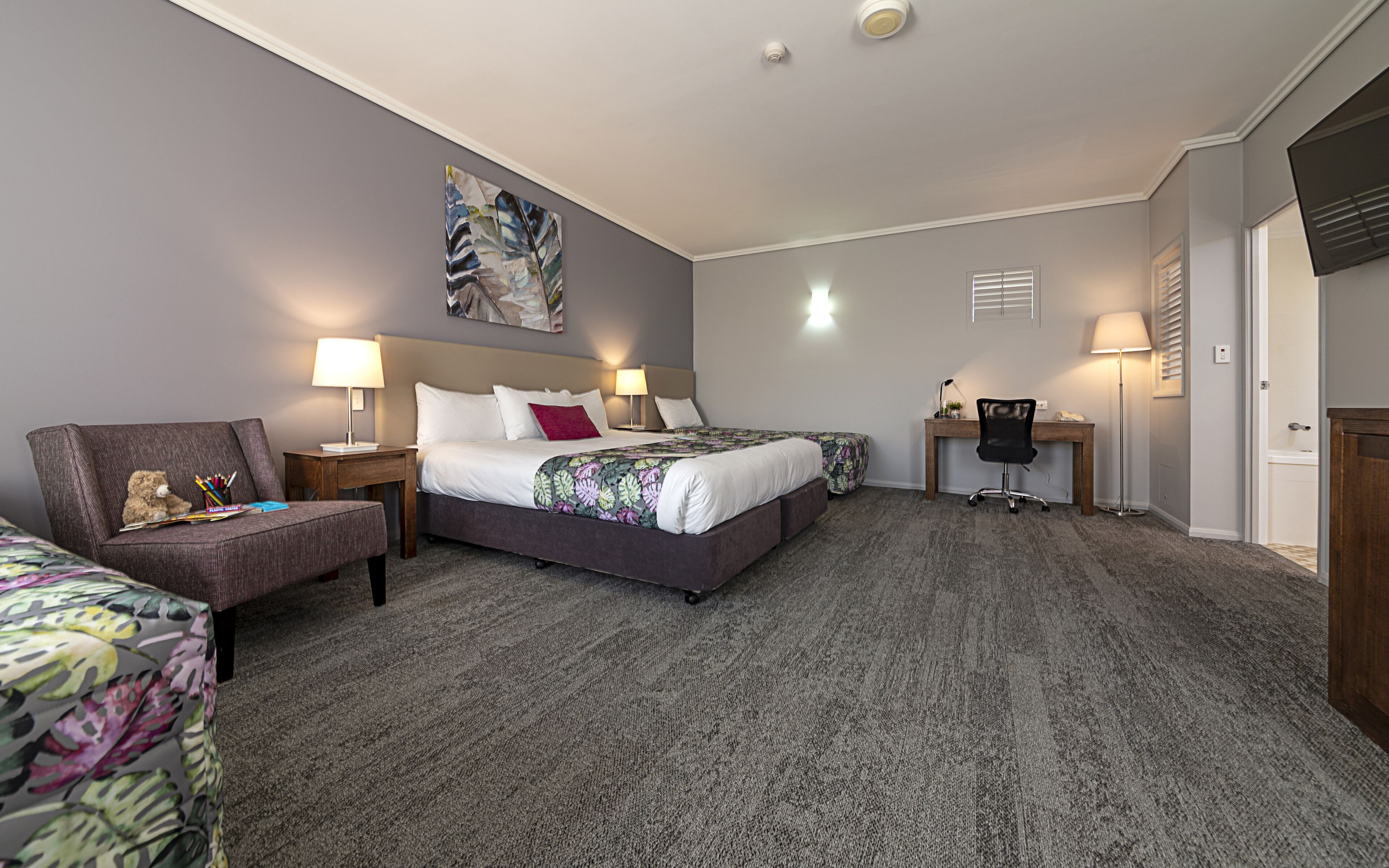 Una habitación de hotel con una cama, un escritorio, una silla y un sofá.
