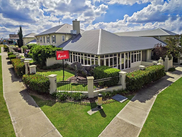 A hotel with a large glass conservatory, a horse statue, and a well-maintained lawn.