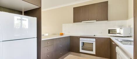 A compact kitchen with a refrigerator, microwave, oven, and dishwasher.
