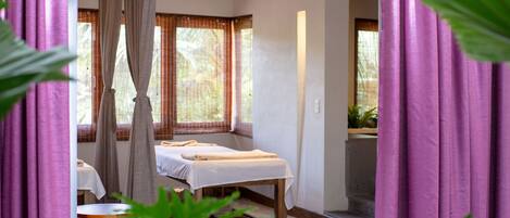 A room with a bed, a table, and a window with curtains.