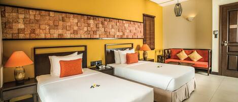 Ein Hotelzimmer mit zwei Betten, einer Ziegelwand, einer Couch und einer Lampe.