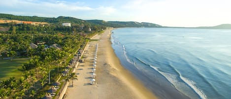 En la playa, arena blanca, sillas reclinables de playa, sombrillas