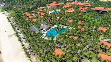 An aerial view of a resort with multiple buildings, a large swimming pool, and a beach.