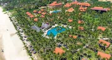 Une vue aérienne d’un complexe hôtelier comprenant plusieurs bâtiments, une grande piscine et une plage.