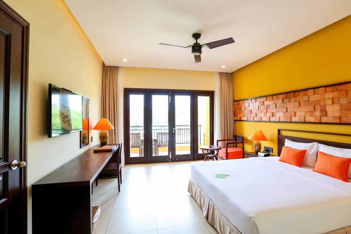 Une chambre d’hôtel équipée d’un lit, d’un bureau, d’une chaise, d’une lampe et d’un balcon avec vue.