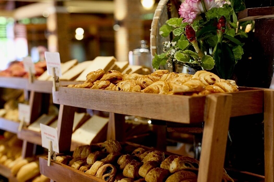 A bakery display with various baked goods and a vase of flowers.
