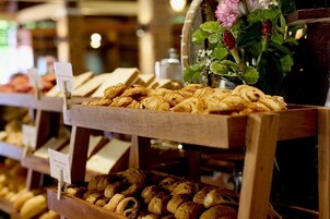 Mostrador de pastelería con diversas opciones de panadería y un florero con flores.
