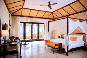 A room with a four-poster bed, a desk with a lamp, and a view through a glass door. - Pandanus Resort (Mui Ne)
