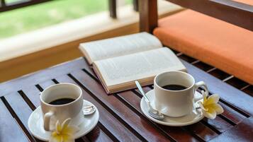 Una mesa de madera con dos tazas blancas de café, un libro y una flor.