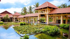A resort with multiple bungalow-style buildings, a central water feature with lily pads, and surrounding greenery. - Pandanus Resort (Mui Ne)