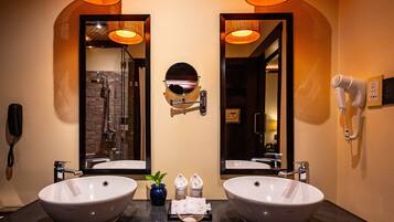 A bathroom with two large sinks, a mirror, a hairdryer, and a phone on the wall.