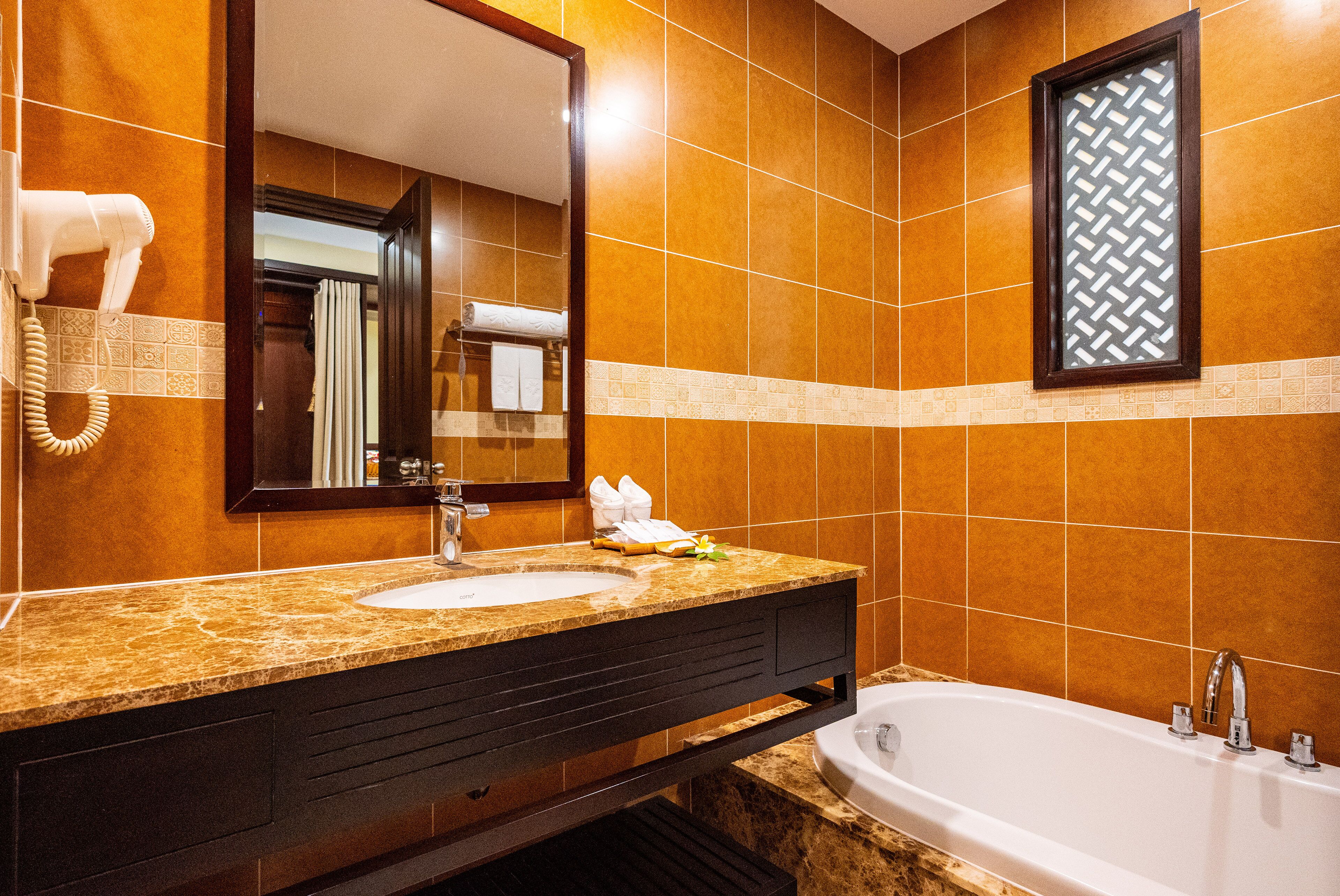 A bathroom with a sink, mirror, and bathtub.