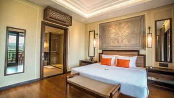 Habitación de hotel con una cama grande, un banco, un espejo y vistas al exterior.