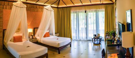 A hotel room with two beds, a desk, a chair, a TV, and a ceiling fan.