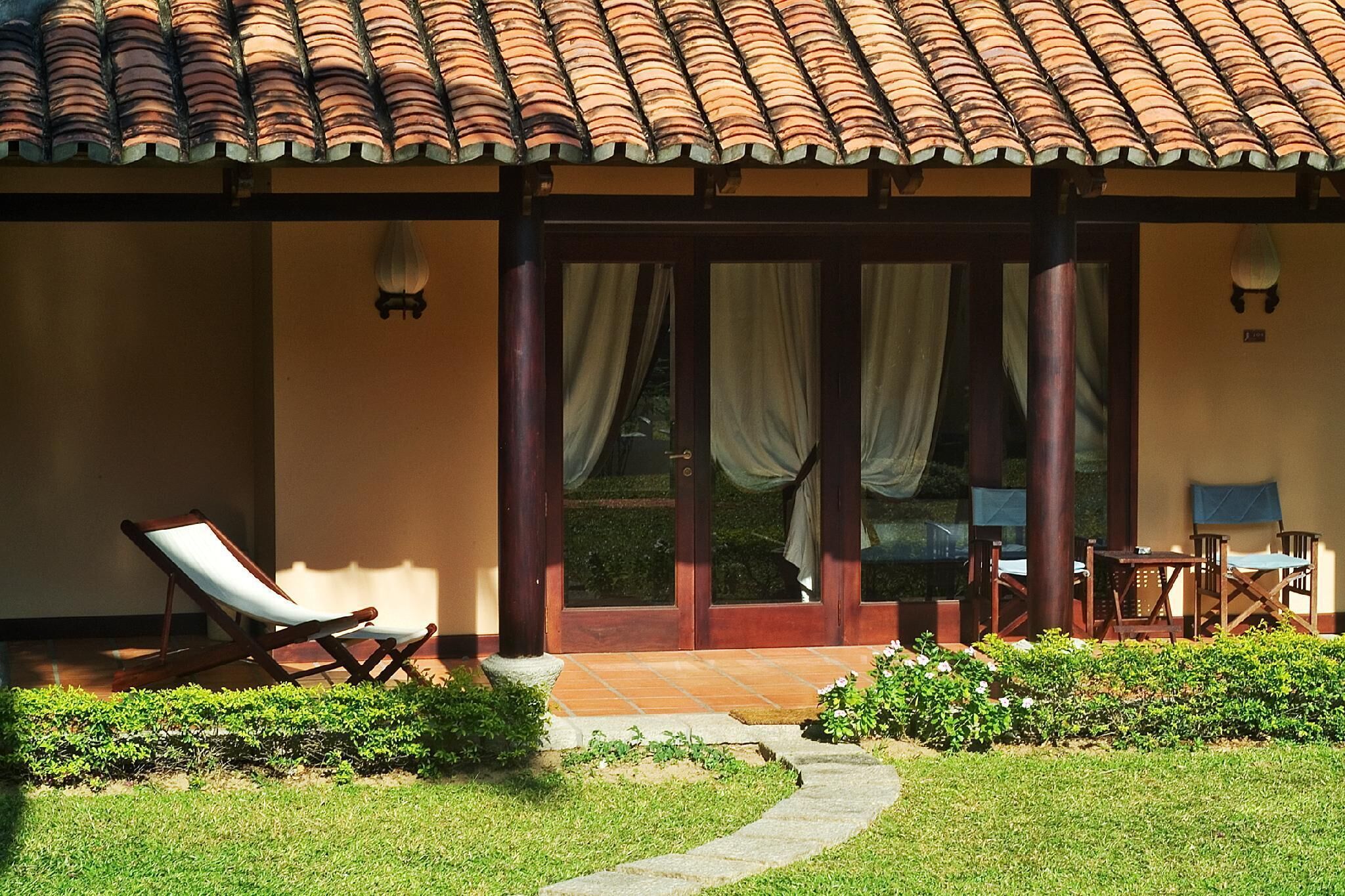 Un espacio de estar al aire libre con techo, que incluye una silla de descanso, una mesa y sillas.