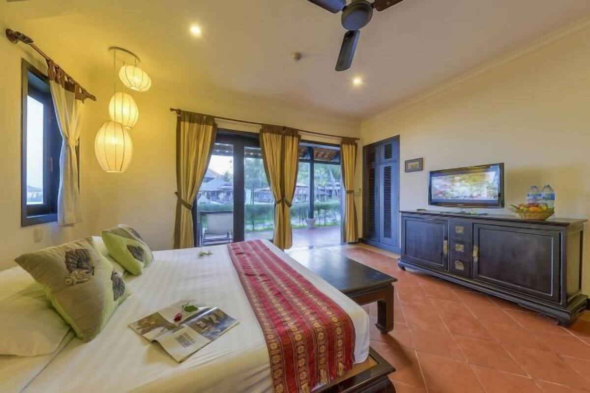 A hotel room with a bed, curtains, a television, and a view through the window.