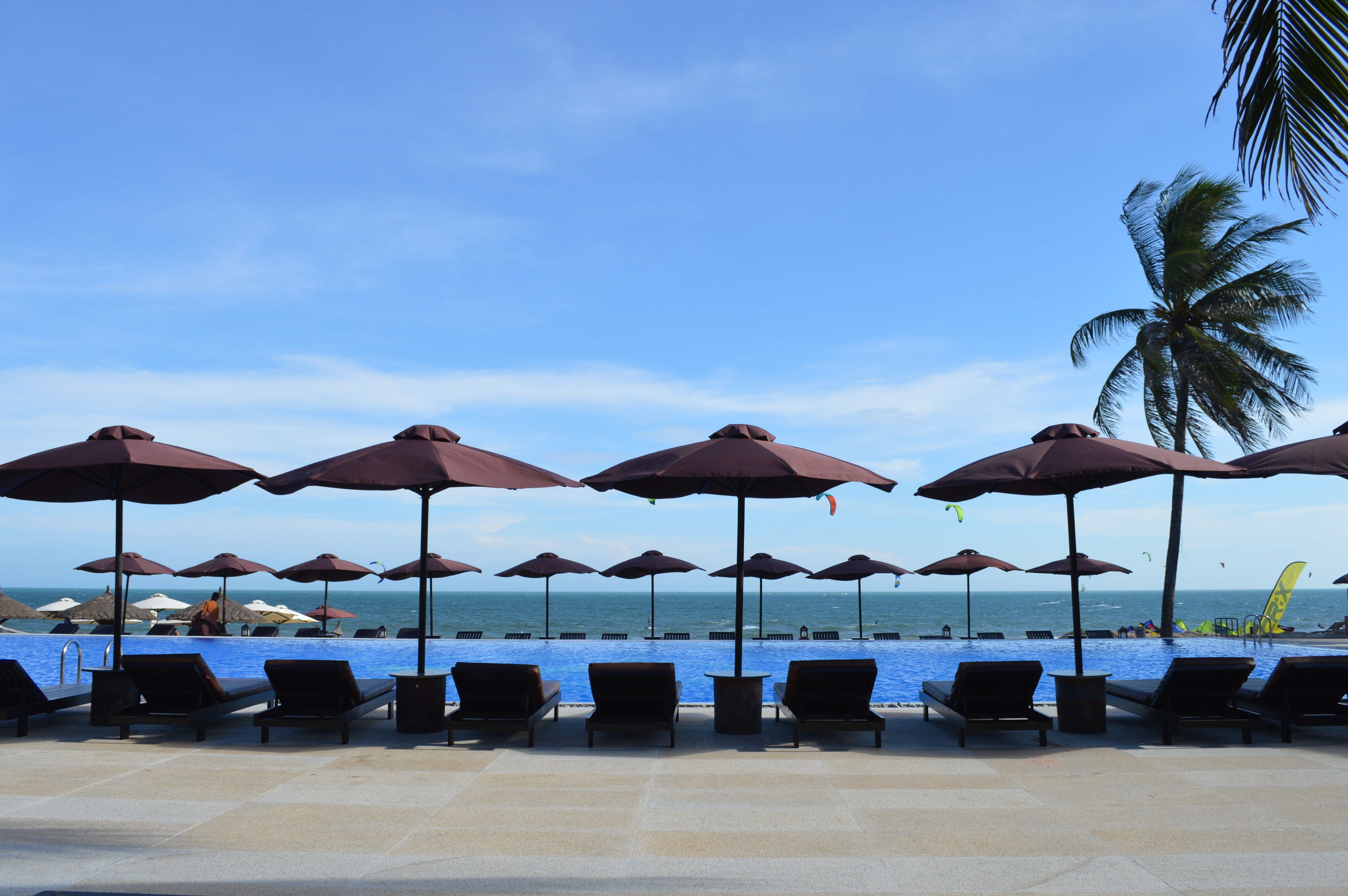 A poolside area with lounge chairs and umbrellas, overlooking the ocean.