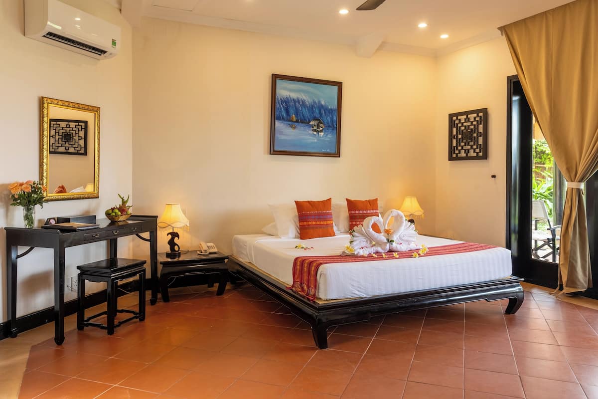 A neatly arranged hotel room with a bed, bedside tables, a desk, and a chair.