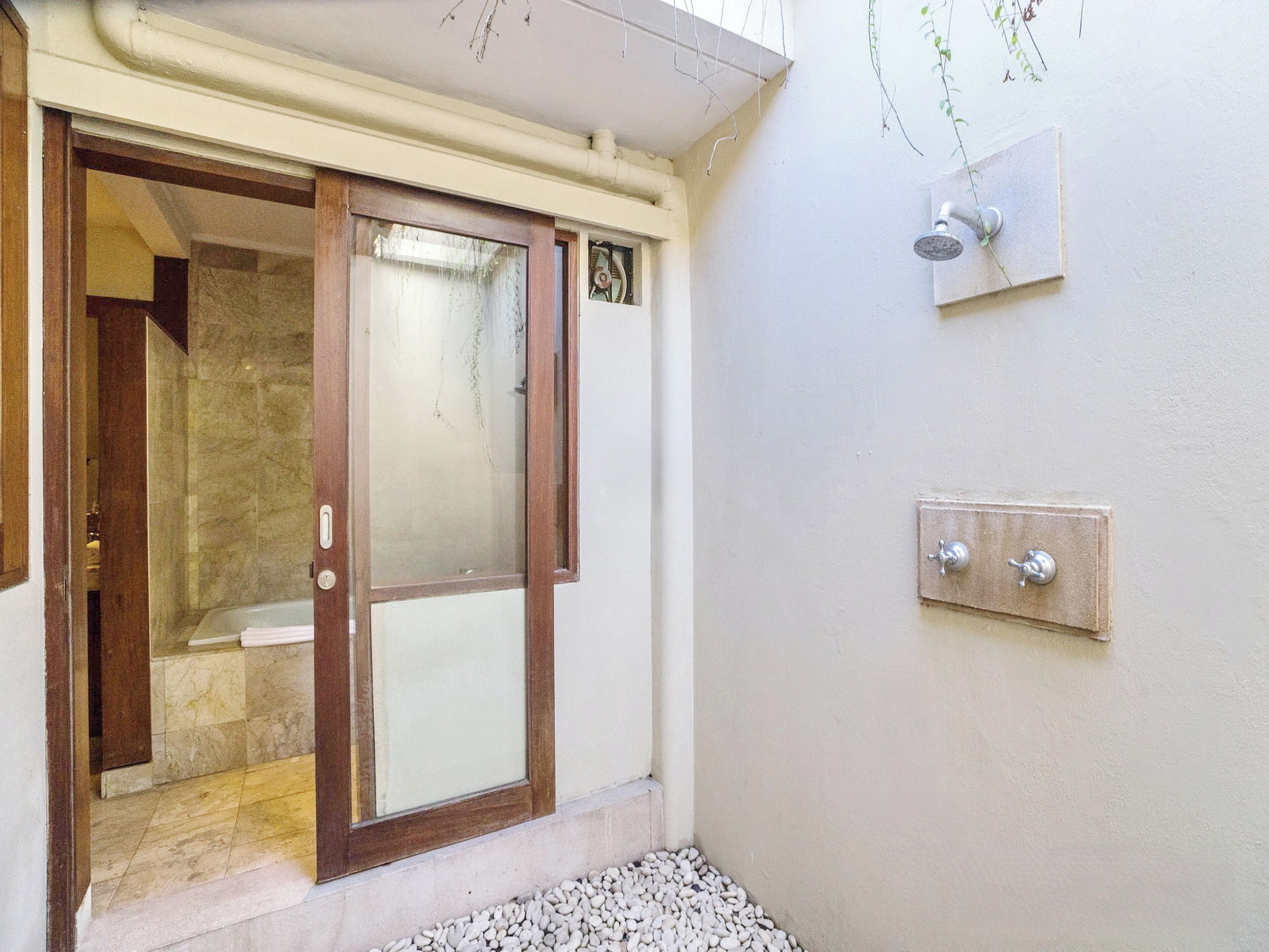 A bathroom with a glass door, a shower, and a wall-mounted faucet.