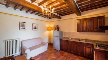 A cozy kitchen with wooden beams, a white sofa, and a tiled floor.